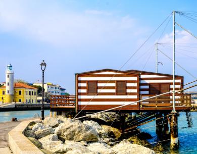 Cabane en bord de mer avec phare et maisons colorées.