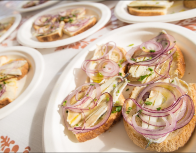 Bruschetta mit roten Zwiebeln, Sardellen und Petersilie auf Papptellern.
