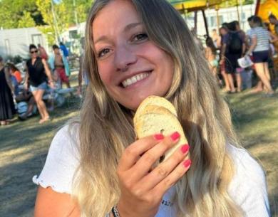 Lächelnde Frau im Freien mit Brot, fröhliche und entspannte Atmosphäre.