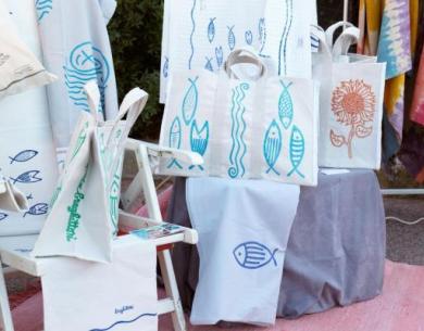 Künstlerische Stofftaschen mit Fisch- und Blumenmotiven, lebendige und fröhliche Farben.