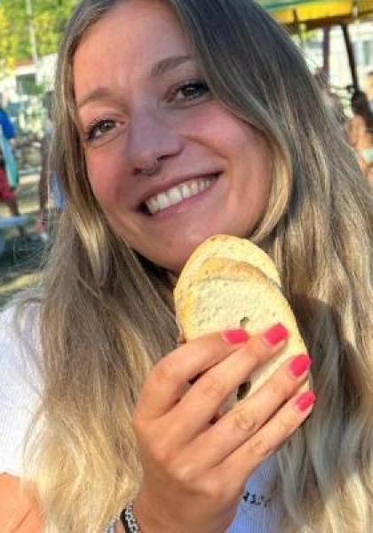 Lächelnde Frau im Freien mit Brot, fröhliche und entspannte Atmosphäre.