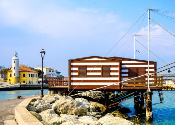 Cabane en bord de mer avec phare et maisons colorées.