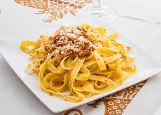 Tagliatelle with ragù and parmesan on a white plate.