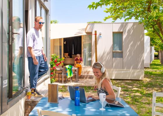 Personnes détendues à l'extérieur, travaillant et discutant près des bungalows.
