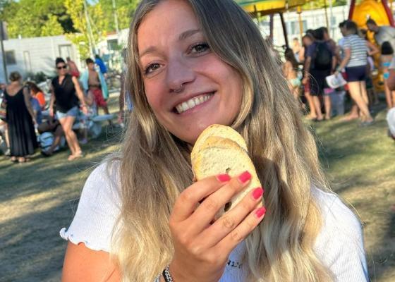 Lächelnde Frau im Freien mit Brot, fröhliche und entspannte Atmosphäre.