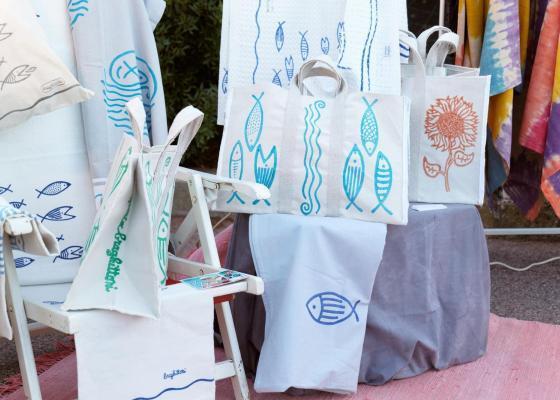 Künstlerische Stofftaschen mit Fisch- und Blumenmotiven, lebendige und fröhliche Farben.
